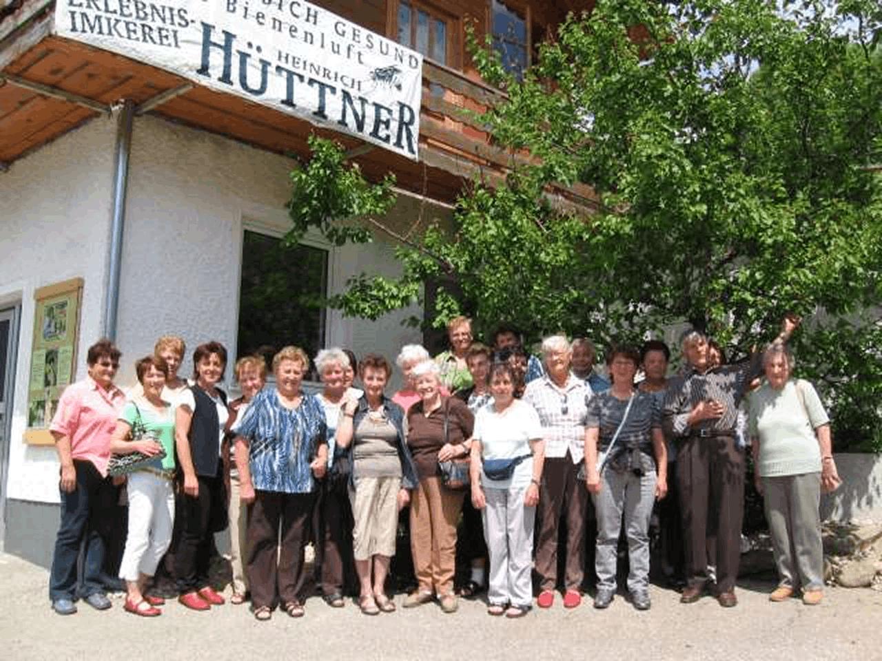 Große Besuchergruppe vor dem Eingang der Erlebnis-Imkerei Hüttner mit dem Schriftzug „Durch Bienenluft gesund – Erlebnis-Imkerei Heinrich Hüttner".